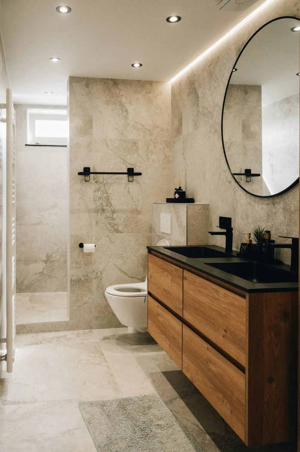 Bathroom with beige stone tiles and an oak vanity
