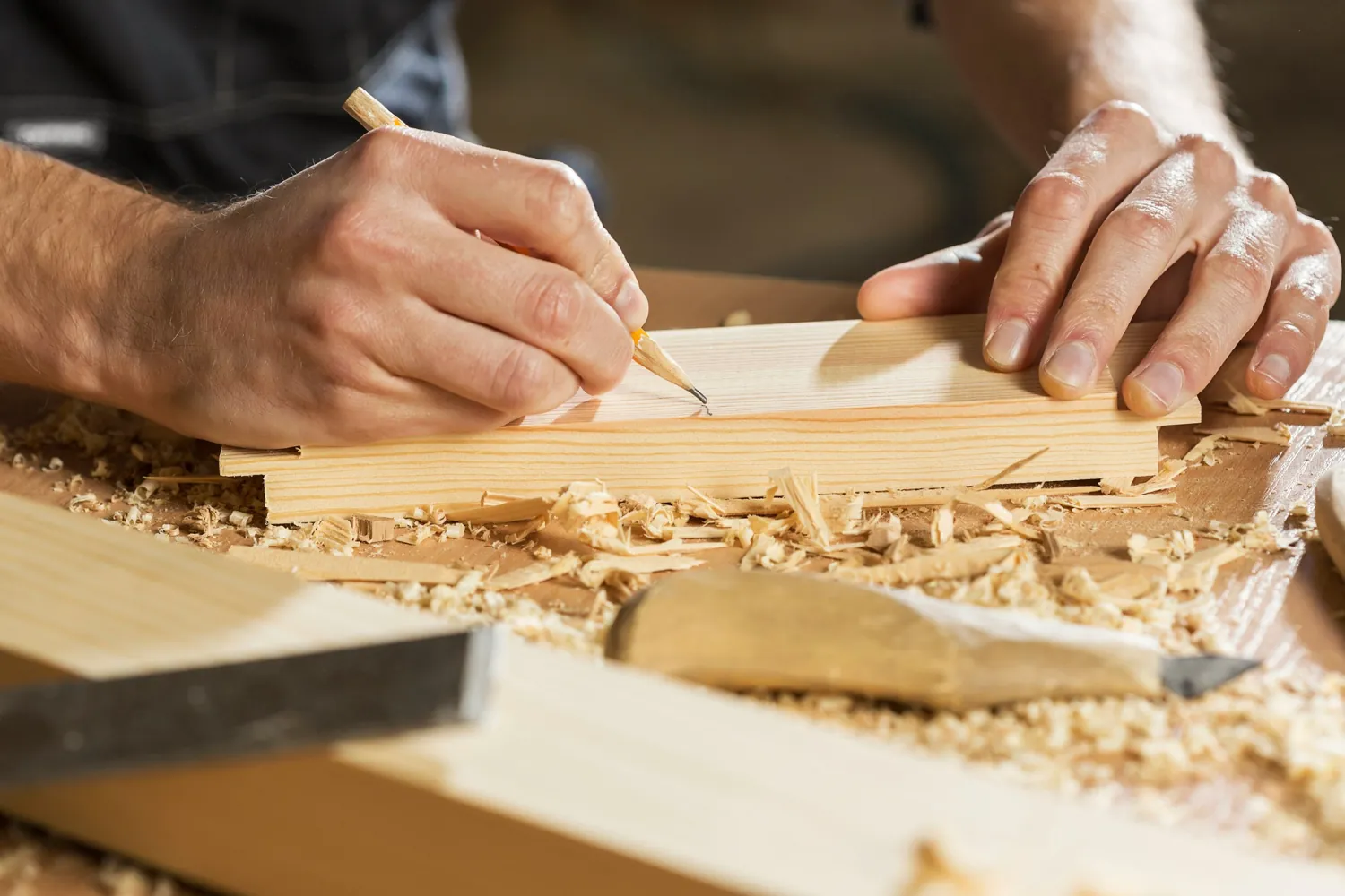 Carpenter marking a wooden board in a workshop
