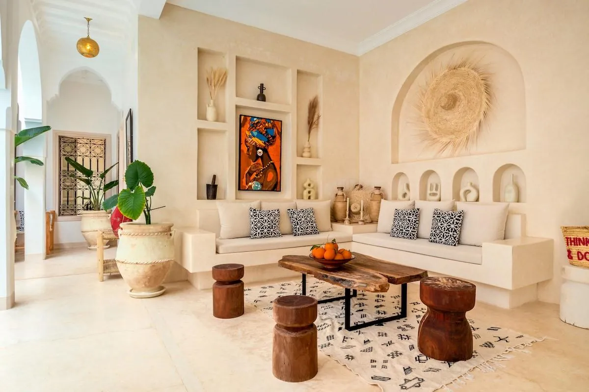 Warm Moroccan living room with cream plastered walls, built-in niches and wooden stools