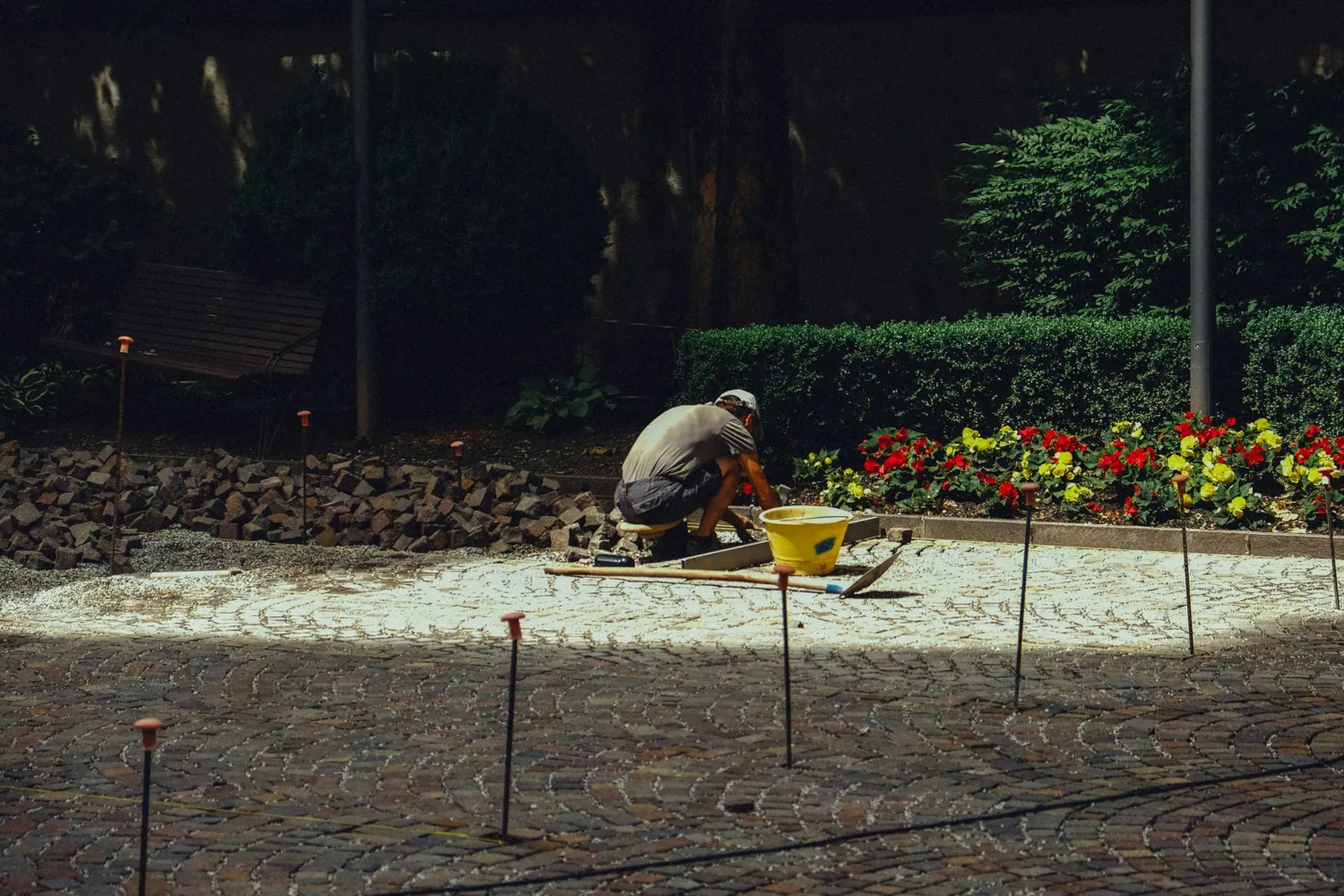 Worker laying paving stones next to a flower bed