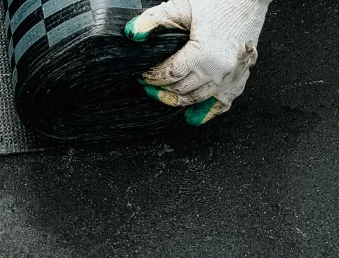 Worker unrolling a waterproofing membrane on a flat roof