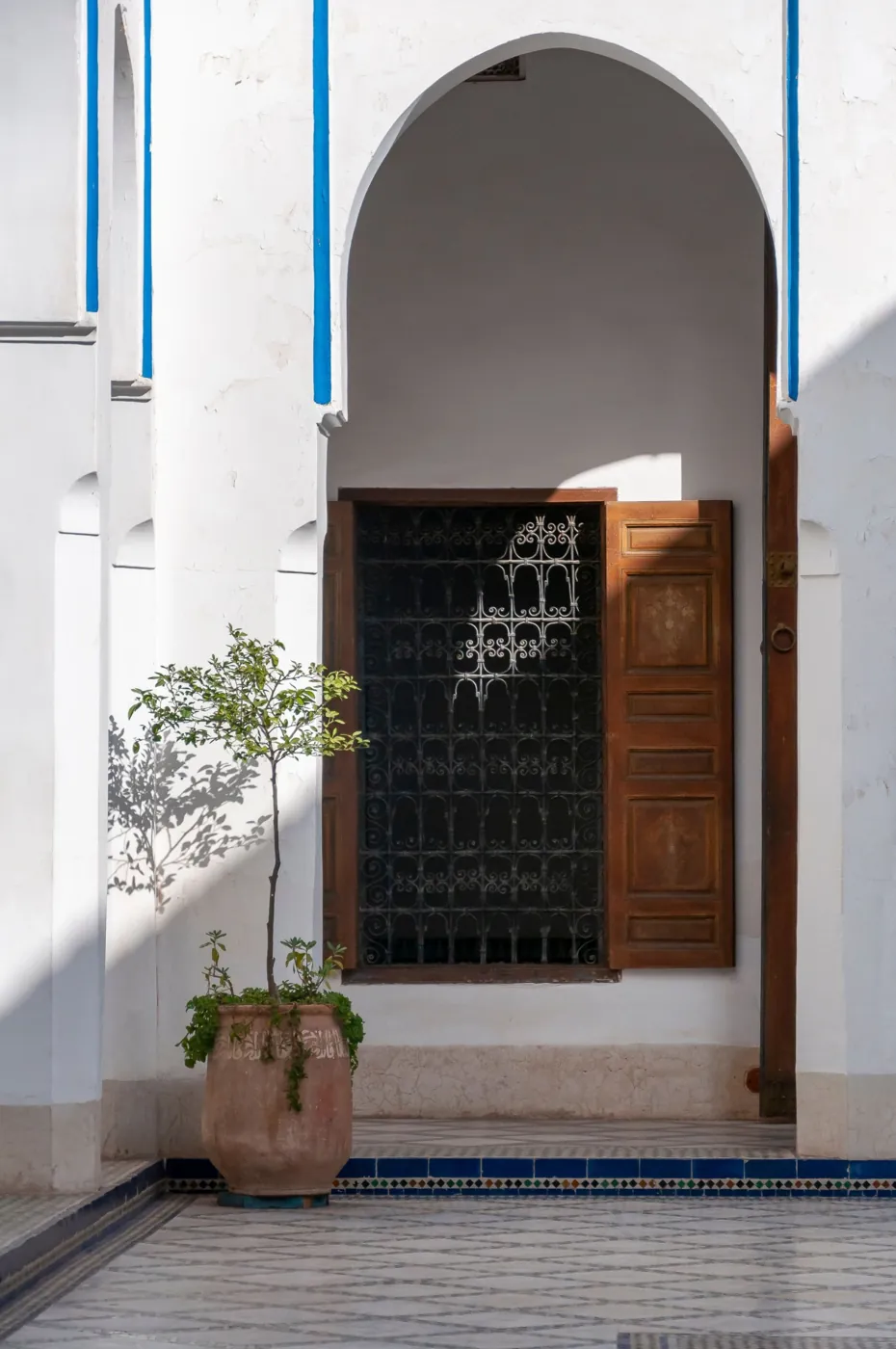 White arch with wooden shutters and wrought-iron window grille